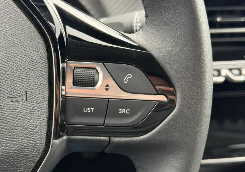 Gros plan sur les commandes noires du volant côté gauche du Peugeot 208 1.2 100ch Allure noir Perla Nera.