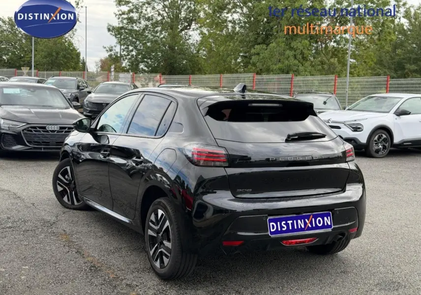 Vue 3/4 arrière d’une Peugeot 208 noire Perla Nera avec vitres teintées et jantes alu en parking.