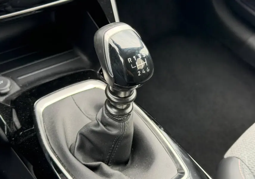 Le levier de vitesses manuel en gros plan de la Peugeot 208 1.2 100ch S&S Allure, intérieur noir.