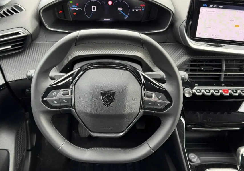 Vue rapprochée du volant multifonction noir et du tableau de bord numérique de la Peugeot 208 1.2 100ch Allure 2025.