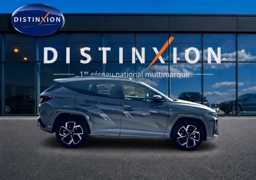 Vue de profil côté gauche du Hyundai Tucson 2026 gris shadow avec jantes alliage distinctives devant un showroom Distinxion.