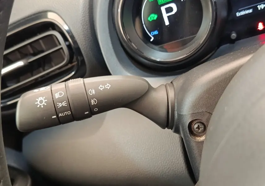Gros plan sur la commande des phares et clignotants à gauche du volant dans le tableau de bord d’une Toyota Yaris hybride blanche 2022.