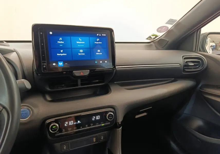 Vue intérieure côté passager de la Toyota Yaris Hybride 116h 2022, avec écran tactile central et climatisation bi-zone.