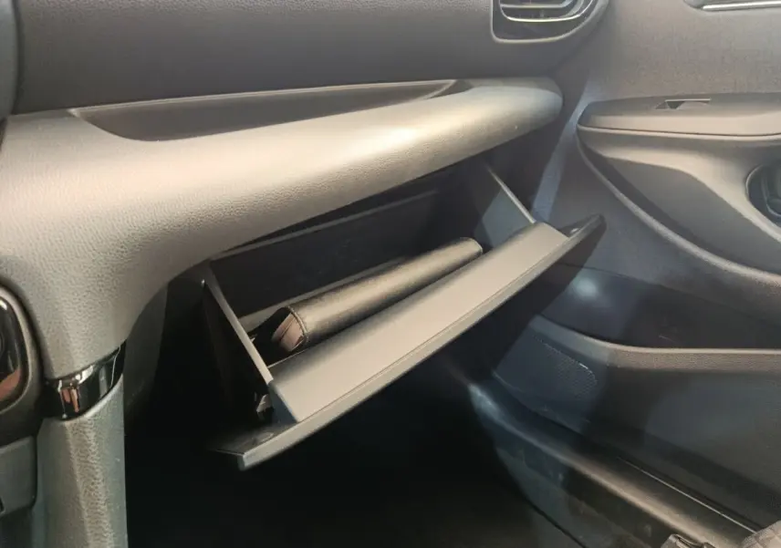 Vue intérieure côté passager de la boîte à gants ouverte de la Toyota Yaris Hybride 116h Collection 2022, finition noire.