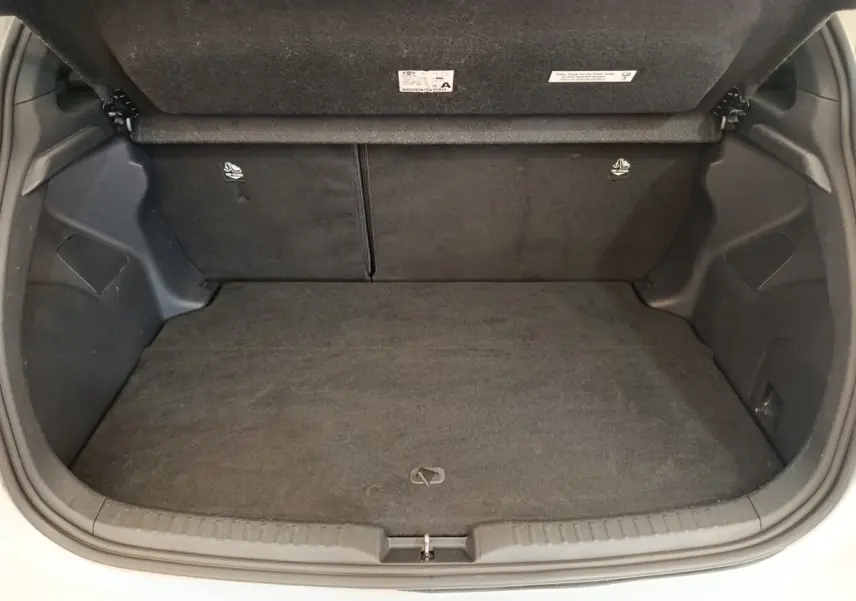 Coffre ouvert de la Toyota Yaris Hybride 116h Collection blanche, montrant l'espace de chargement vide et la banquette arrière rabattable.
