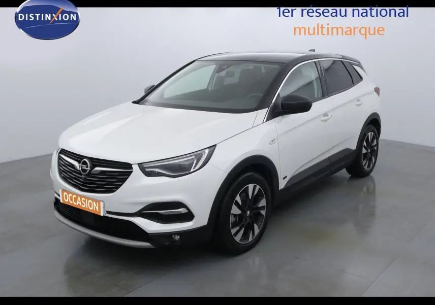 Opel Grandland X blanc perle métal vu en 3/4 avant droit, avec toit noir et jantes bicolores distinctives.