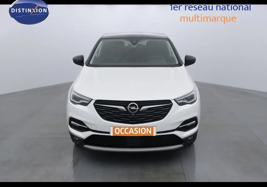 Vue frontale d'un Opel Grandland X blanc perle métal avec calandre noire et toit panoramique sombre.