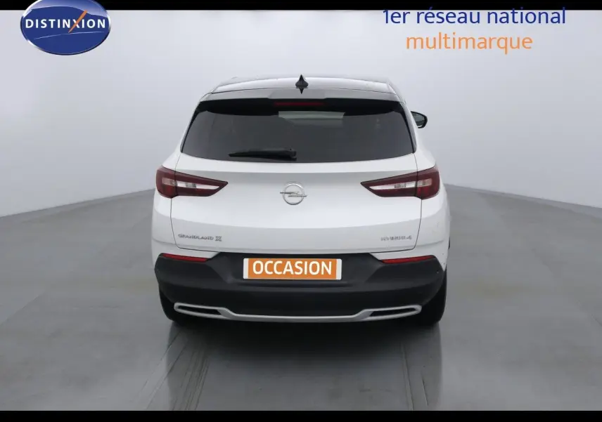 Vue arrière d'un Opel Grandland X blanc perle métal avec logo et plaques distinctives visibles.
