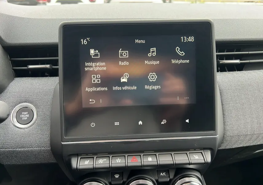 Écran tactile central et tableau de bord de la Renault Clio V TCE 90 Techno 2025 avec bouton start/stop et finition tissu gris.