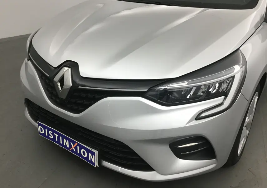 Vue 3/4 avant d'une Renault Clio V gris platine mettant en valeur ses phares LED et la calandre noire distinctive.