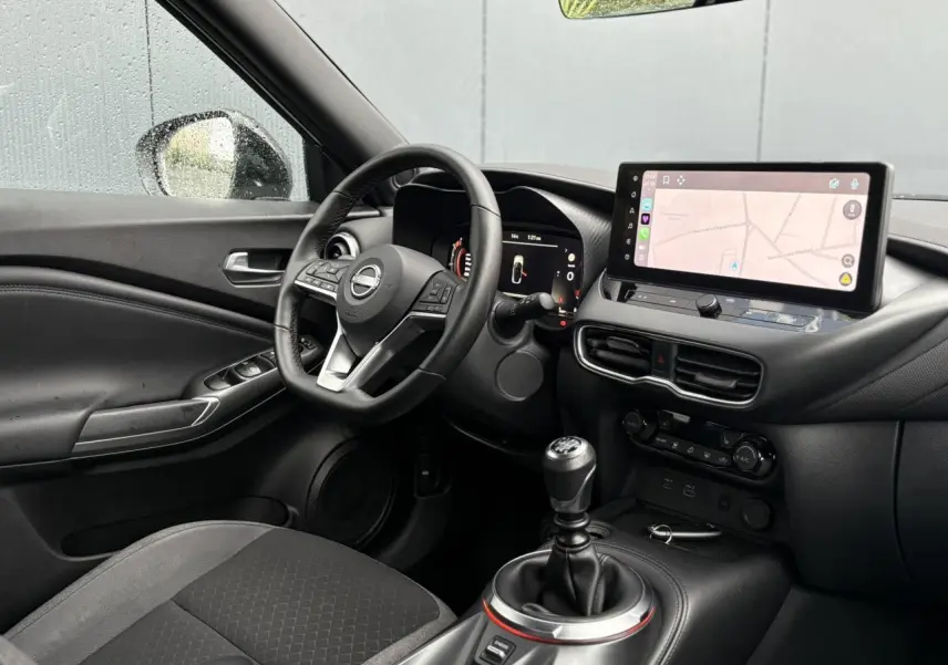 Intérieur du Nissan Juke 2025 vu côté conducteur, volant cuir, écran tactile 12,3 pouces avec navigation affichée.