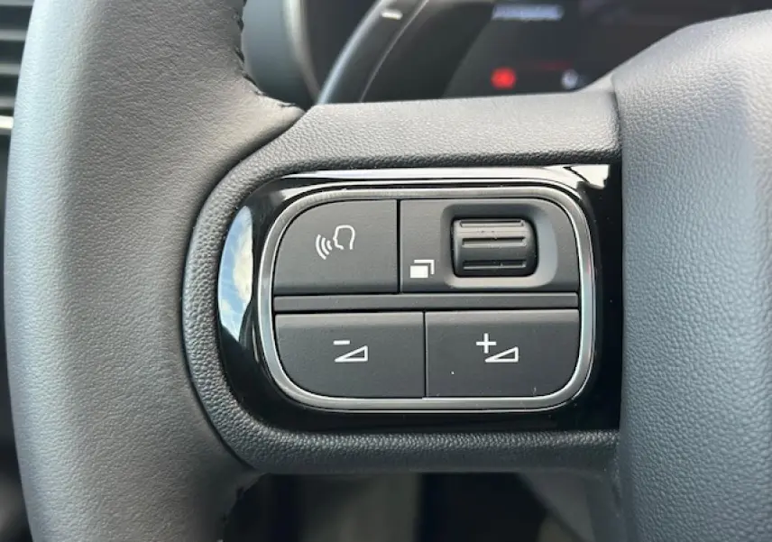 Gros plan sur les commandes du volant en cuir du Citroën C5 Aircross gris platinium 2025, boutons multifonctions.