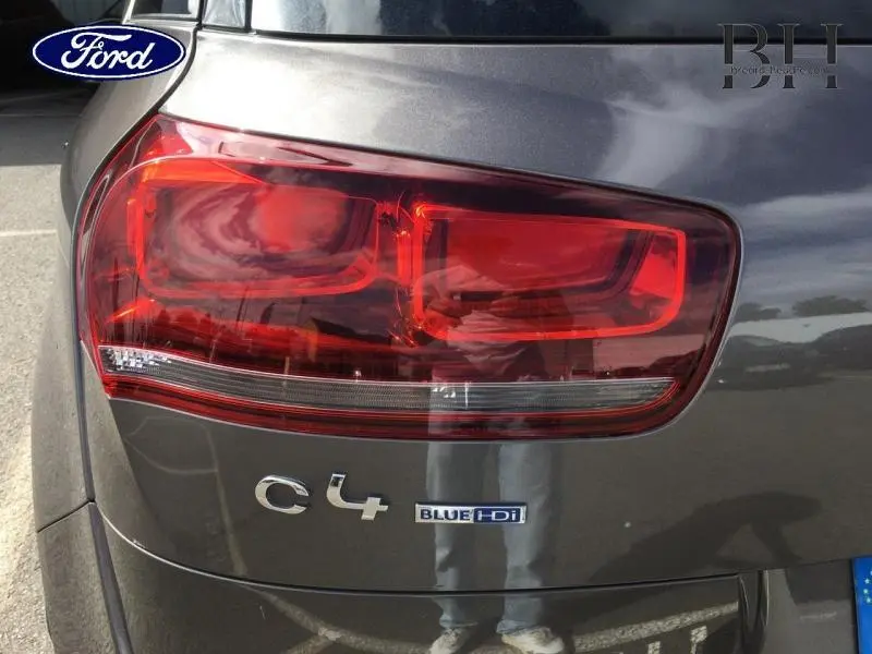 Gros plan sur le feu arrière gauche d’une Citroën C4 Picasso gris Shark avec logo BlueHDi visible.