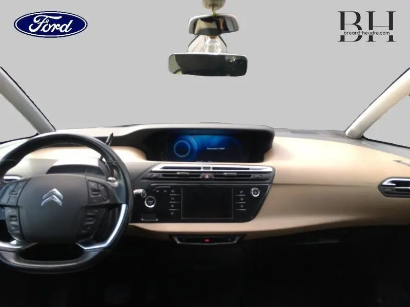 Vue intérieure avant du tableau de bord beige et noir de la Citroën C4 Picasso avec volant multifonction et écran central tactile.