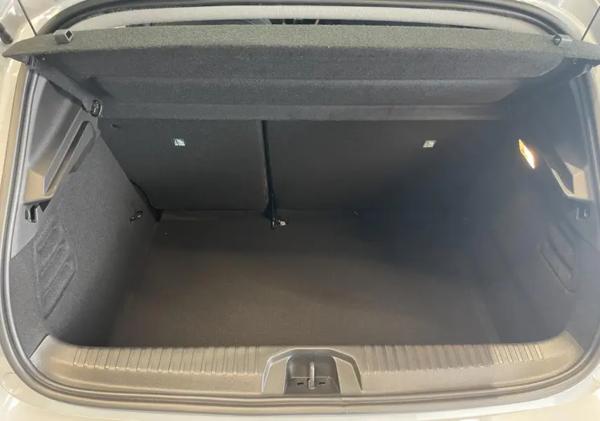 Coffre ouvert vu de l'arrière d'une Renault Clio 1.5 Blue dCi 2025 gris Rafale, intérieur noir et éclairage latéral.