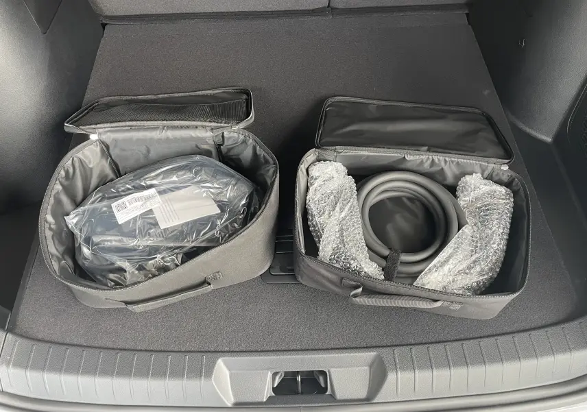 Vue du coffre du BYD SEAL U 2025 avec deux sacs de rangement contenant câbles de recharge et accessoires.