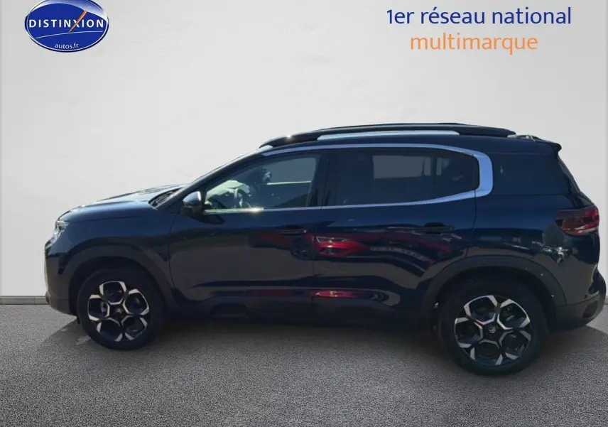 Vue de profil côté gauche d'un Citroën C5 Aircross bleu eclipse avec jantes alliage et barres de toit noires.