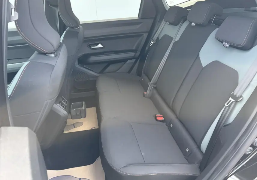 Vue latérale intérieure sur la banquette arrière noire du Dacia Bigster 2026 avec appuie-têtes et ceintures visibles.