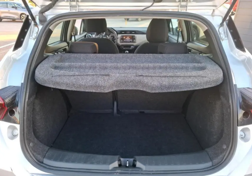 Vue arrière du coffre ouvert d'une Nissan Micra gris clair 2022, avec cache-bagages et intérieur noir visible.