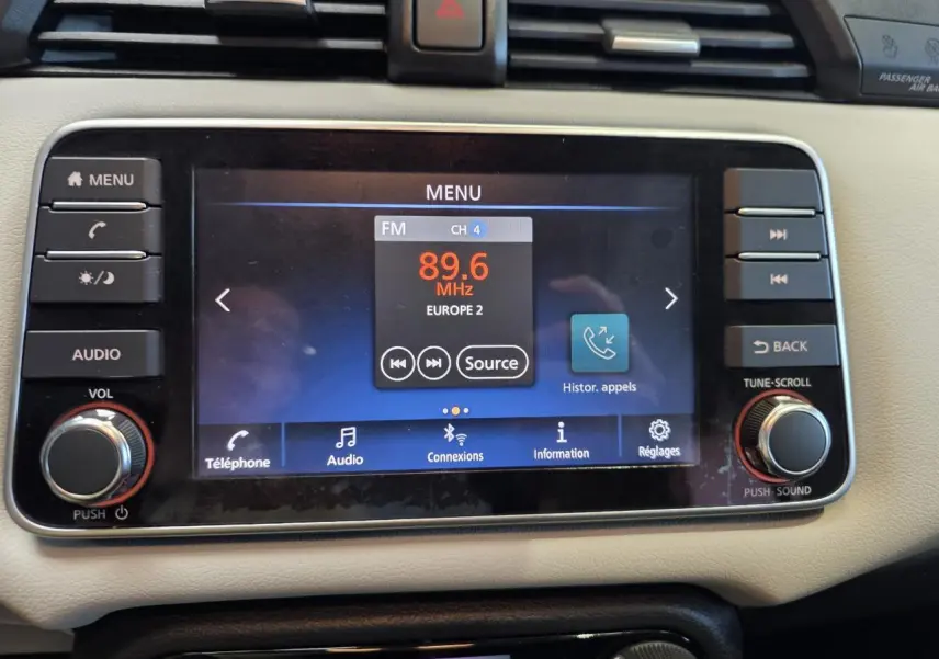 Écran tactile central de la Nissan Micra 2022, vue frontale, tableau de bord beige avec commandes audio et téléphone.