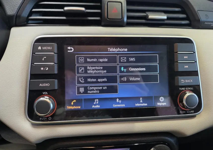 Gros plan sur l'écran tactile central beige de la Nissan Micra 2022 affichant le menu téléphone et les commandes audio.