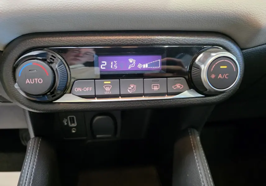 Gros plan sur la commande de climatisation automatique de la Nissan Micra gris clair, avec affichage digital à 21,5°C.
