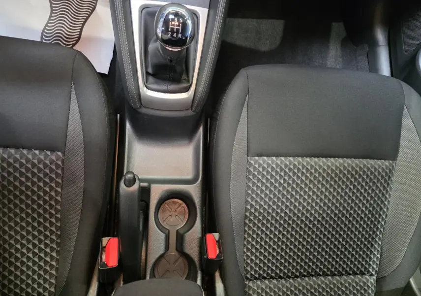 Vue intérieure centrée sur la console centrale et les sièges avant en tissu noir de la Nissan Micra 2022 avec boîte manuelle.