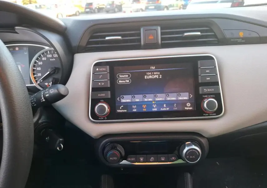 Vue intérieure du tableau de bord beige et noir de la Nissan Micra 2022 avec écran tactile radio et commandes climatisation.