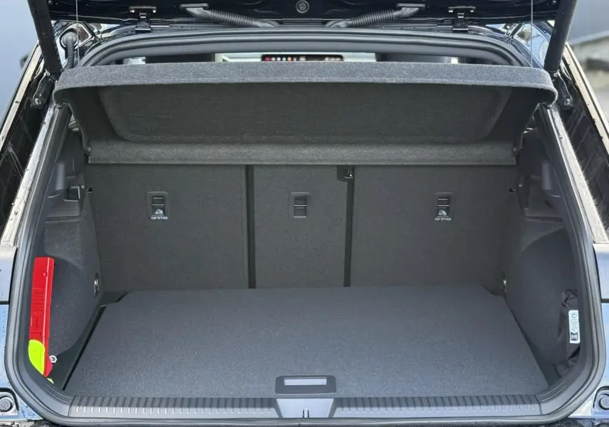 Coffre ouvert en vue arrière d’un Volkswagen T-Roc noir Ébène, montrant l’espace de chargement et la tablette de coffre relevée.