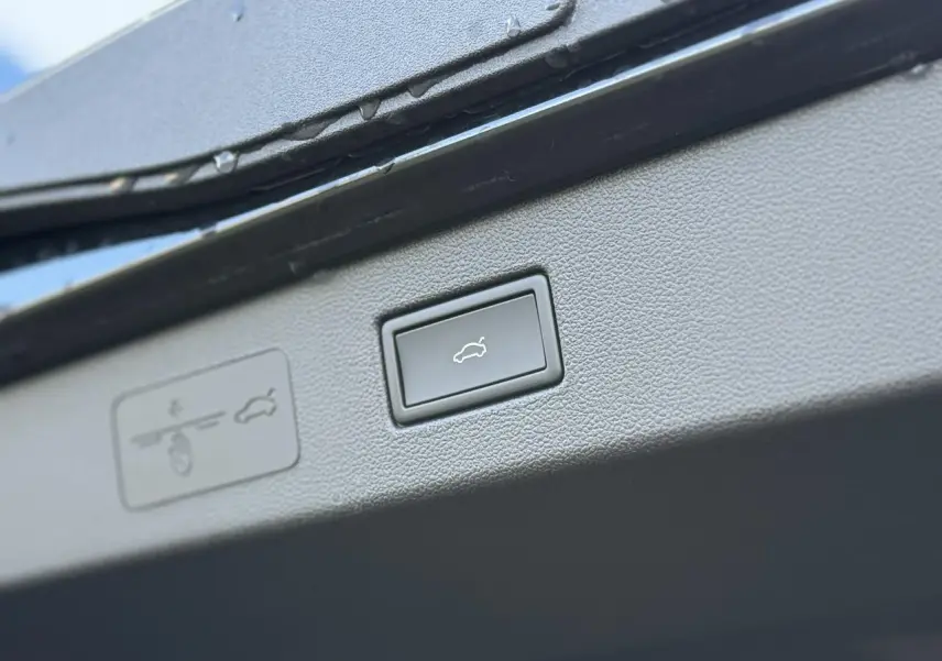 Gros plan sur le bouton d'ouverture électrique du hayon du Volkswagen T-Roc 2026, intérieur noir.