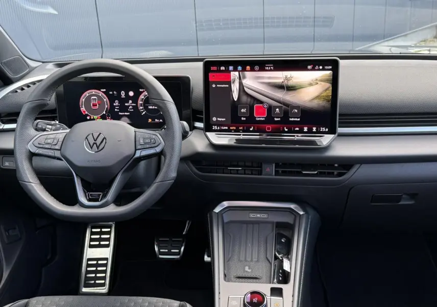 Vue frontale de l'habitacle du Volkswagen T-Roc 2026 avec volant multifonction, écran tactile et pédalier sport en acier inox.