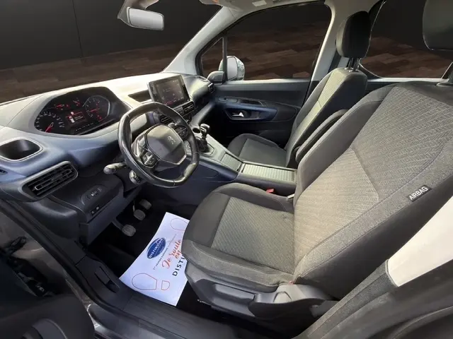 Vue intérieure côté conducteur du Peugeot Rifter gris foncé 2020, montrant le tableau de bord digital et les sièges tissu avec airbags latéraux.