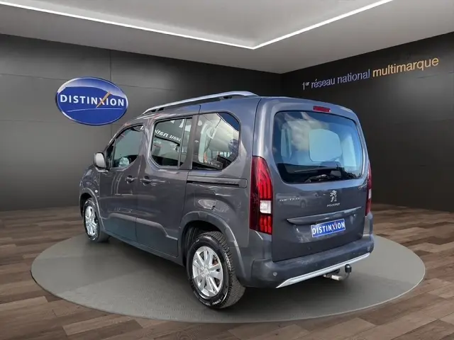 Vue 3/4 arrière droite d’un Peugeot Rifter gris foncé 2020 avec hayon, feux verticaux et attelage visible.