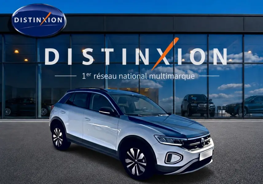 Volkswagen T-Roc blanc vue 3/4 avant droit devant un bâtiment avec logo Distinxion.