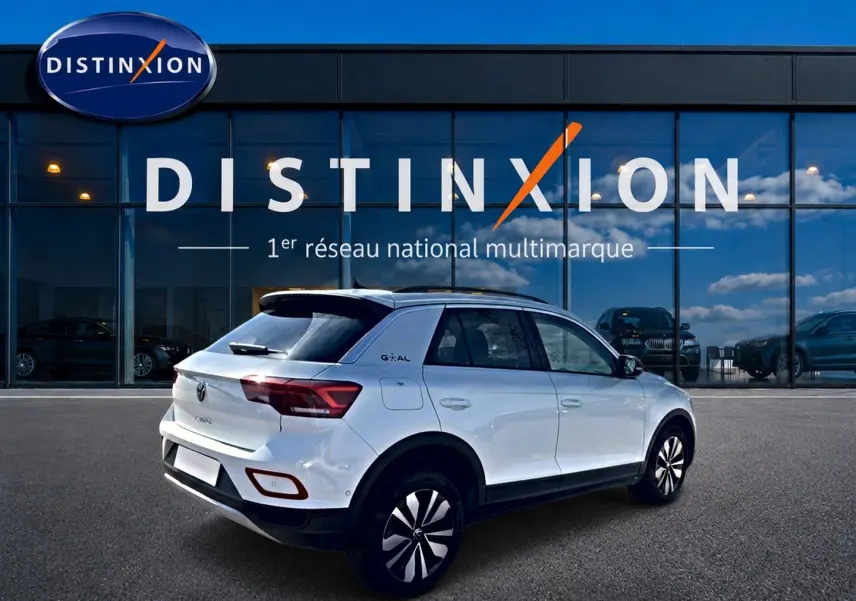 Volkswagen T-Roc blanc vue 3/4 arrière droit, avec jantes alu et toit noir devant showroom Distinxion.