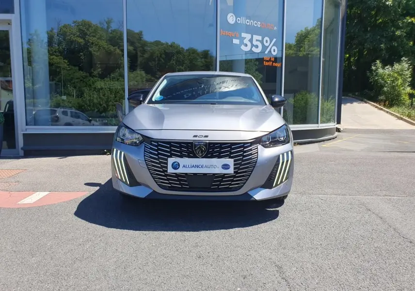 Vue frontale d'une Peugeot 208 gris Artense avec calandre noire et feux diurnes LED en griffes.