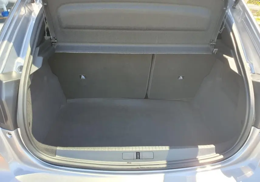 Coffre ouvert vu de l'arrière d'une Peugeot 208 1.2 Hybrid 110 gris Artense, intérieur noir et propre.
