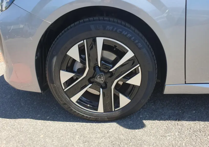Gros plan sur la roue avant droite d’une Peugeot 208 gris Artense avec jante alliage bi-ton diamantée.