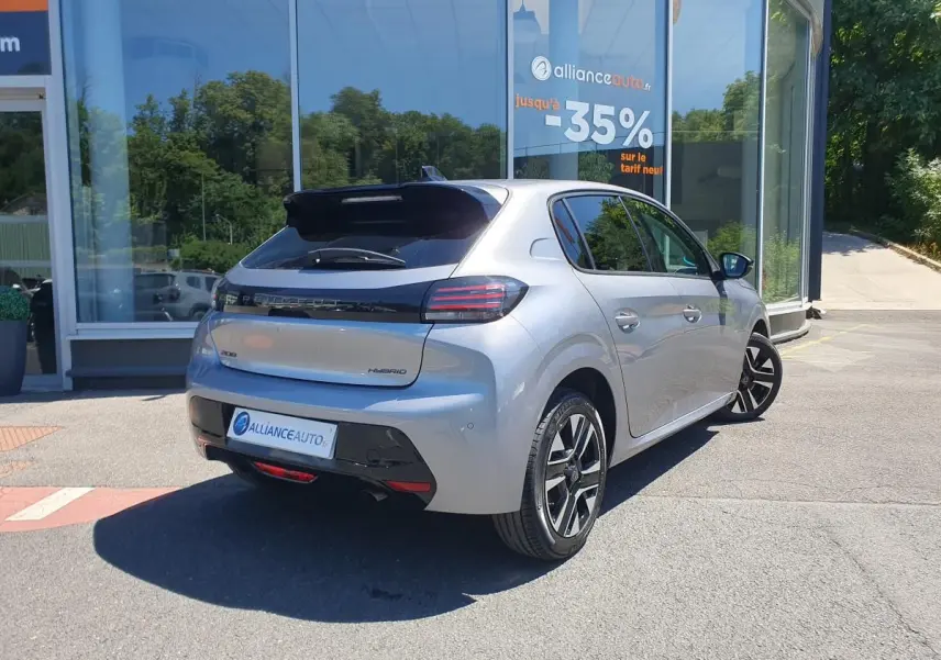 Vue 3/4 arrière droite d'une Peugeot 208 gris Artense avec jantes alliage bi-tons, garée devant un showroom.