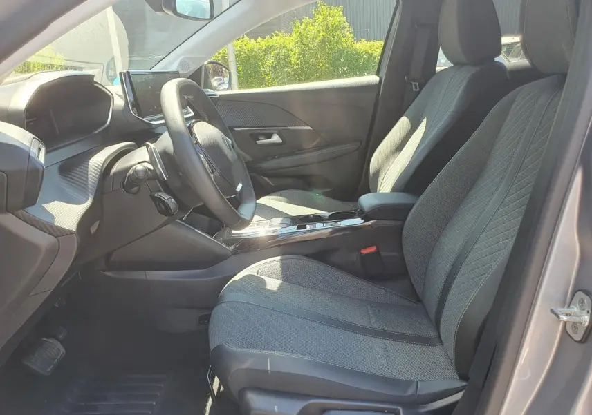 Intérieur de la Peugeot 208 1.2 Hybrid 110 DCS6 Allure vu côté conducteur, sièges gris et tableau de bord moderne.