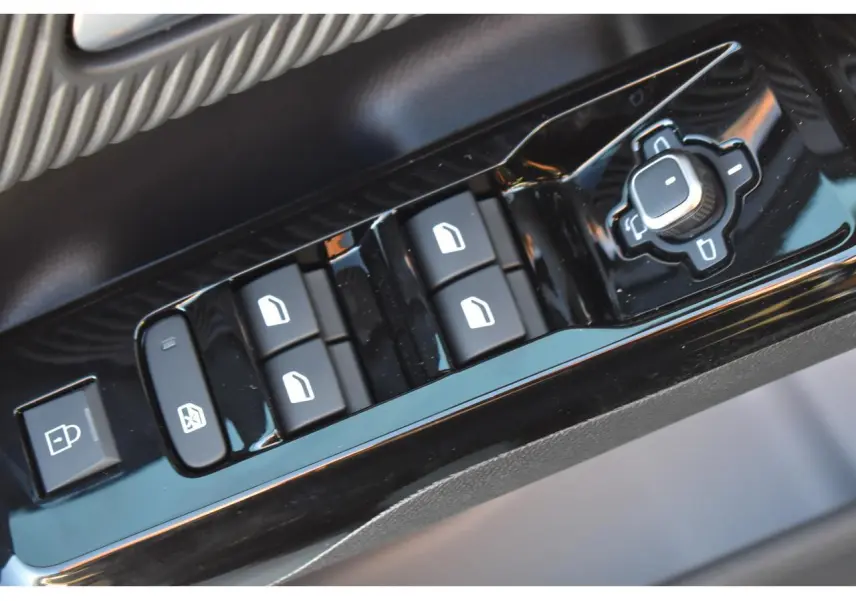 Gros plan sur les commandes de lève-vitres et réglages des rétroviseurs côté conducteur du Citroën C5 Aircross hybride gris.