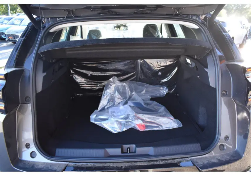 Vue arrière du coffre ouvert d'un Citroën C5 Aircross gris, montrant un espace de chargement vide avec un objet emballé en plastique.
