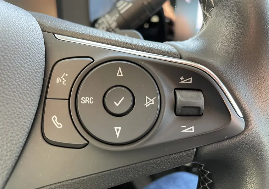 Gros plan sur les commandes audio et téléphone au volant noir de l'Opel Mokka 2023 finition Elegance Business.