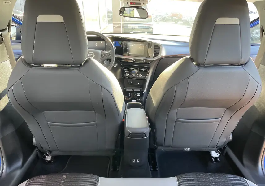 Vue intérieure arrière de l'Opel Mokka bleu voltak 2023, sièges avant noirs et tableau de bord moderne avec écran tactile.