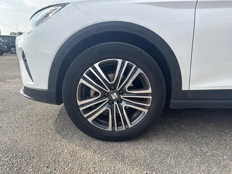 Gros plan sur la roue avant gauche d'un SEAT Arona blanc Nevada avec jante alliage 17 pouces au design dynamique.