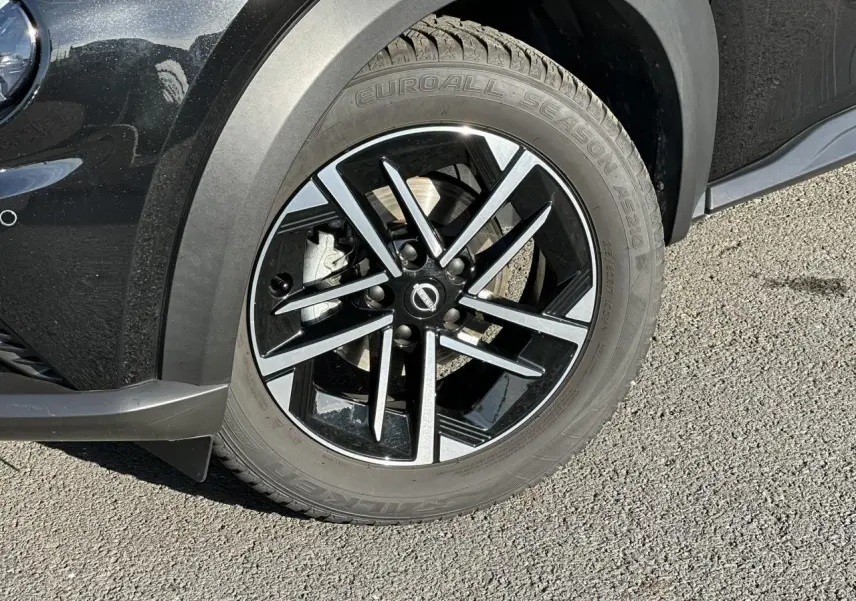 Gros plan sur la jante alliage 17'' noire et argentée du côté avant droit du Nissan Juke noir 2025.