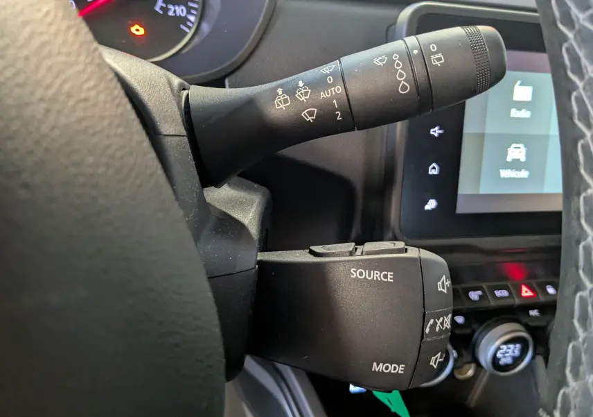 Gros plan sur les commandes au volant du Dacia Duster gris 2023, avec leviers de réglage essuie-glace et audio visibles.