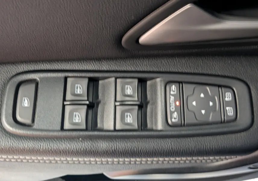 Commande des vitres électriques et réglages des rétroviseurs sur la porte côté conducteur du Dacia Duster gris 2023.