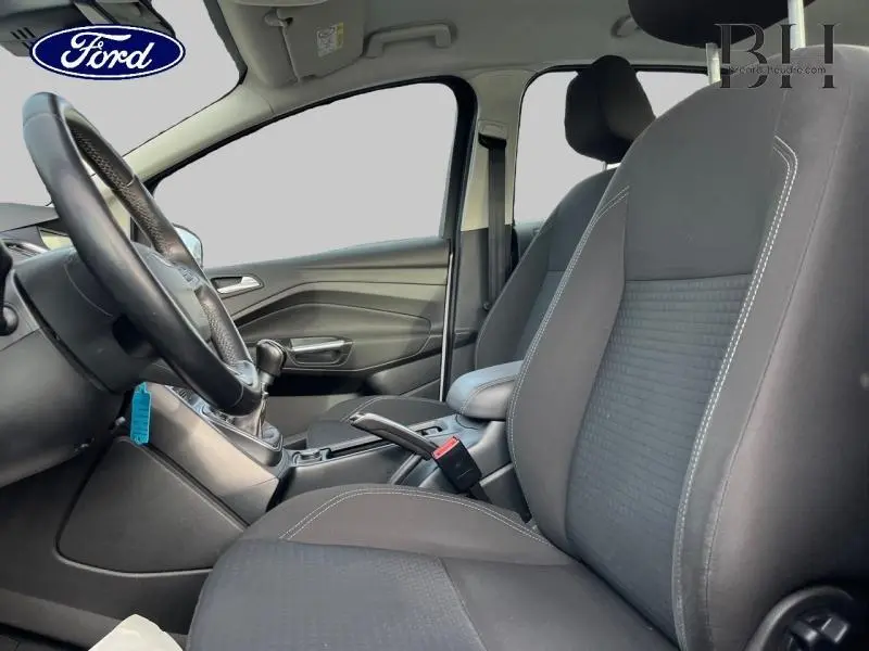 Vue intérieure côté gauche du Ford C-MAX 2018, sièges noirs avec coutures blanches et volant cuir multifonction.