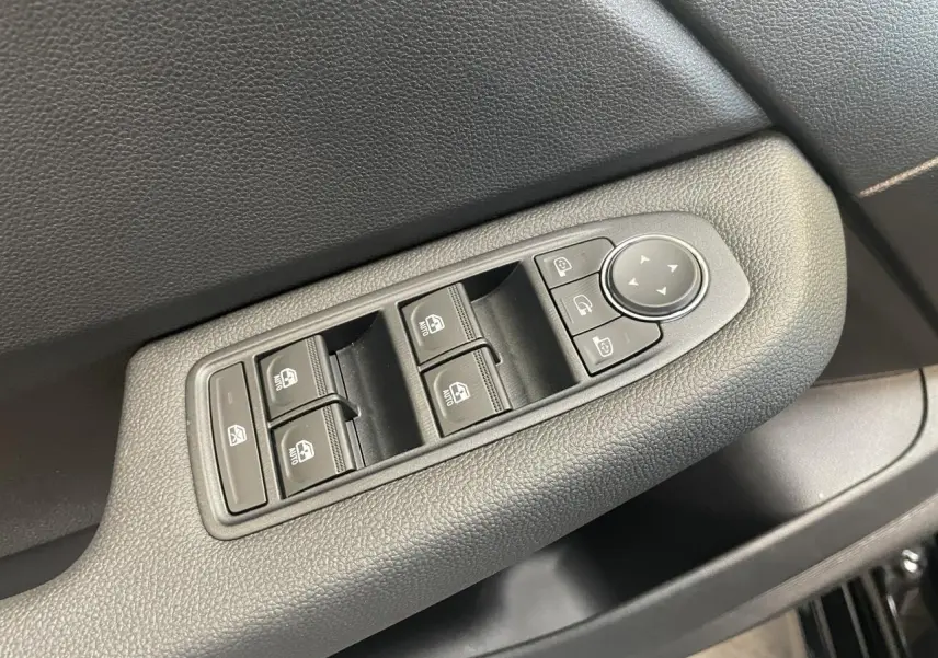 Gros plan sur la commande des vitres électriques et rétroviseurs sur la porte côté conducteur d’une Renault Clio noire étoile.